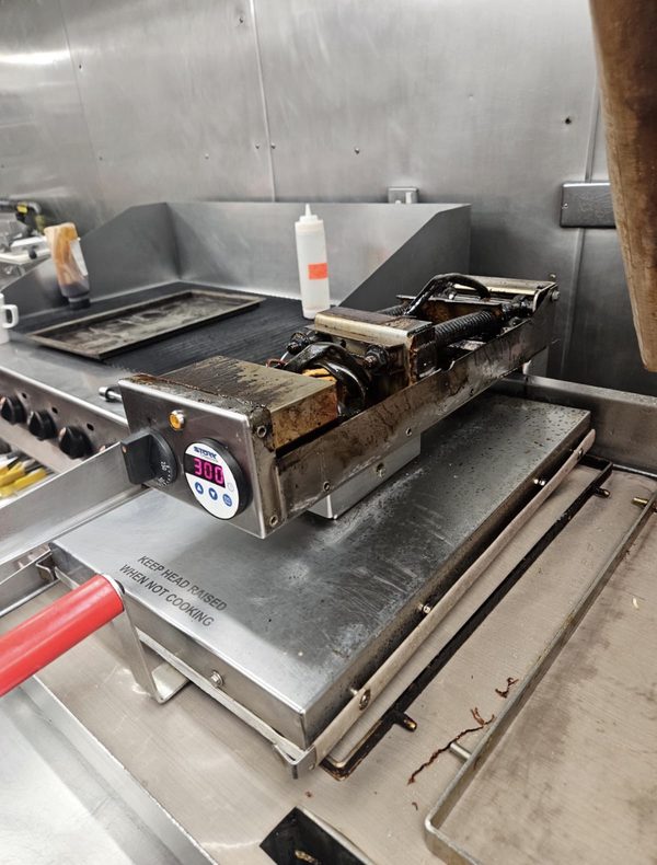 Clamshell grill press on a commercial griddle, repaired and back up to temperature