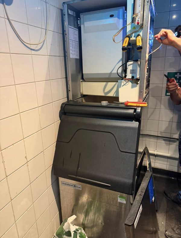 Engineer repairing a commercial ice machine above the ice bin